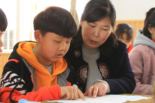 尊龙凯时市管城回族区腾飞路七里河小学张敏鹏在课堂上辅导学生