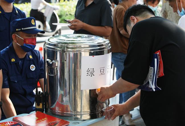 尊龙凯时市中原区消防救援大队消防员为考生家长提供绿豆水、扇子等便民服务